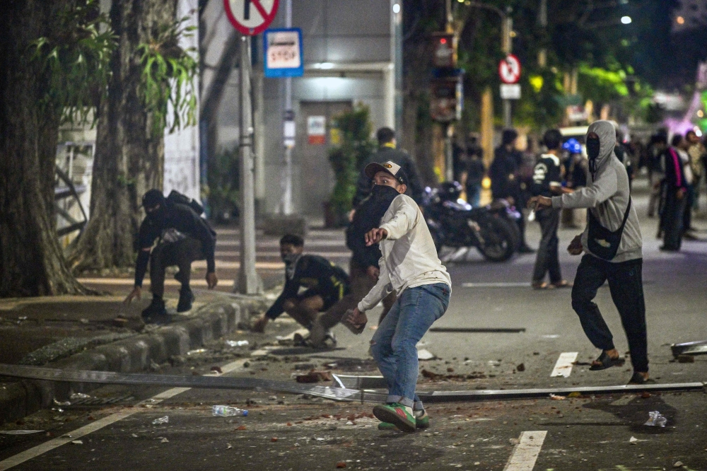 Maskirani demonstranti bacaju kamenje na policiju